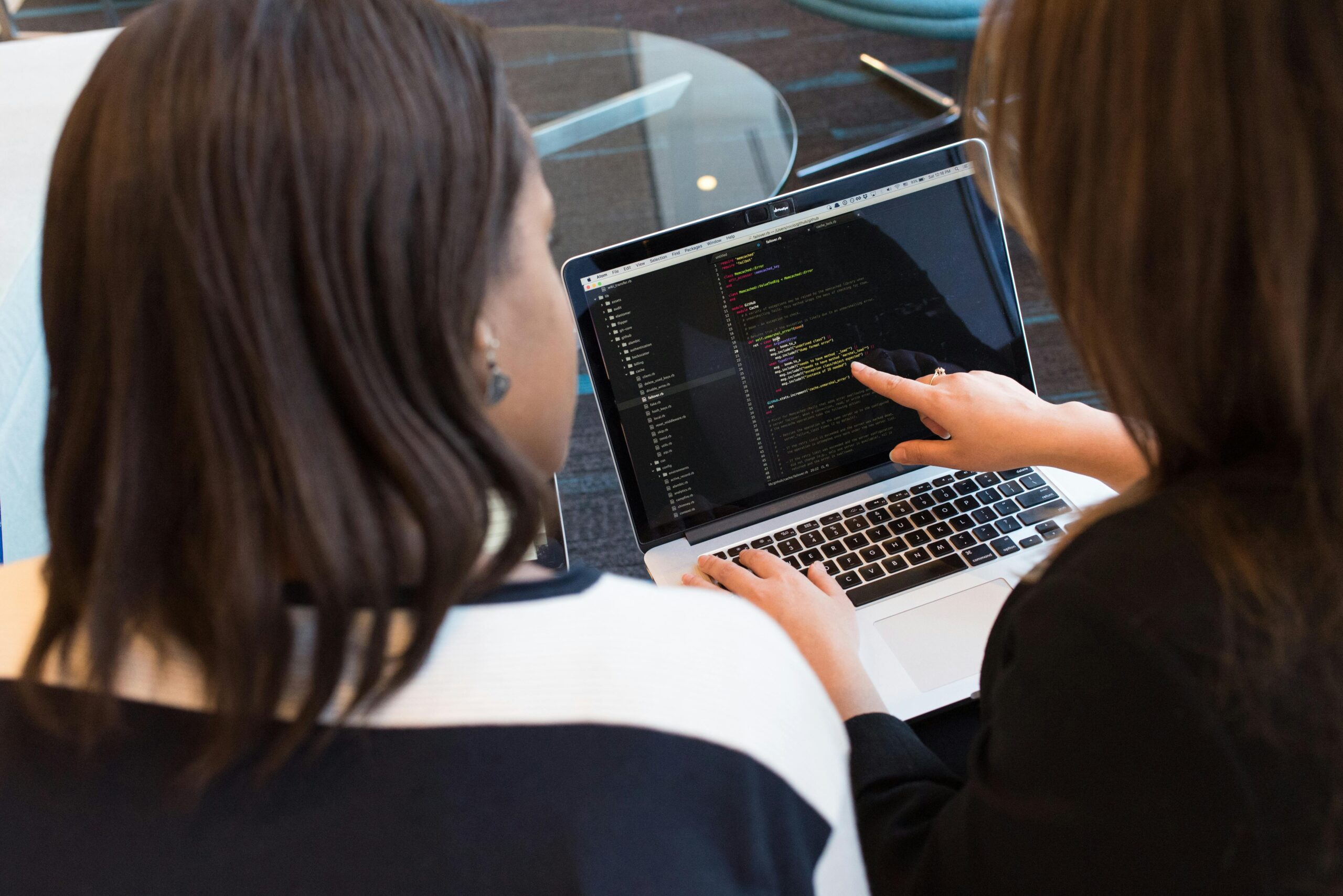 two people reviewing code on a laptop screen